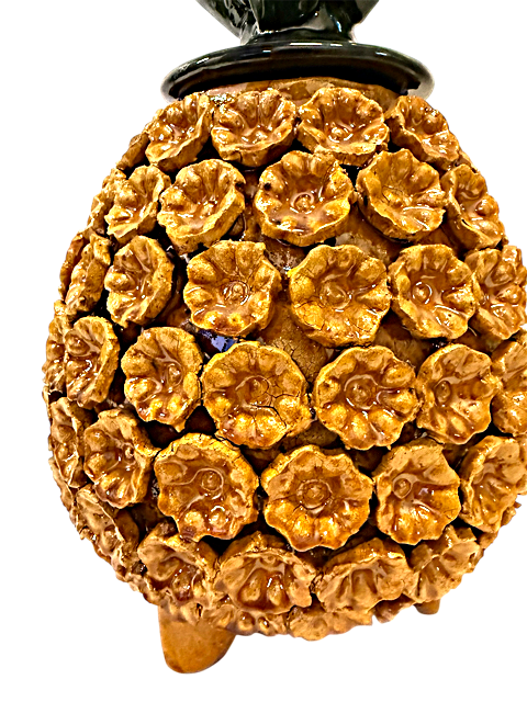 Close-up del intrincado pastillaje manual con técnica de flor en una piña de cerámica, detalle artístico de alfarería michoacana de alta calidad.