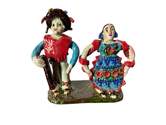 Escultura de barro vidriado de Doña Luz; figuras de pueblos originarios con hombre en gabán rojo vibrante y mujer con mandil azul cobalto, pieza auténtica de la colección Mansion Iturbe Artisans.