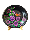 Vista frontal completa de una batea redonda de madera negra con diseño central de mariposa monarca y flores moradas, una obra de arte popular purépecha de Mansión Iturbe Artisans Collection.