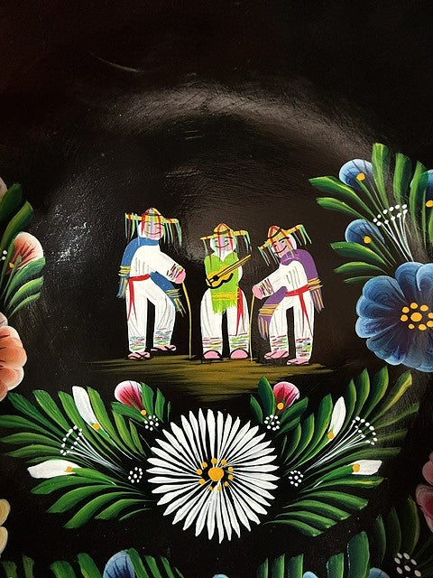 Primer plano del centro de una batea de madera negra pintada a mano que muestra el detalle de los personajes tradicionales de la Danza de los Viejitos de Jarácuaro.