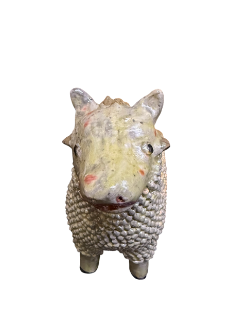 Primer plano frontal de un borrego de barro vidriado modelado a mano por la maestra Doña Luz. Se aprecia el detalle minucioso de cientos de pequeñas esferas de barro aplicadas individualmente para crear la lana en color blanco hueso.