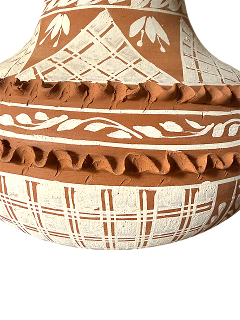 Primer plano del relieve de pastillaje ondulado en color terracota y cenefa de hojas pintada a mano en blanco grisáceo sobre un jarrón artesanal de Patamban.