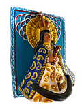 Primer plano en ángulo de la escultura de la Virgen en alto relieve sobre el retablo azul. Se aprecia la textura del barro modelado a mano y la pintura detallada de los diablitos y las flores que la rodean. Pieza única de Mansión Iturbe Artisans Collection.