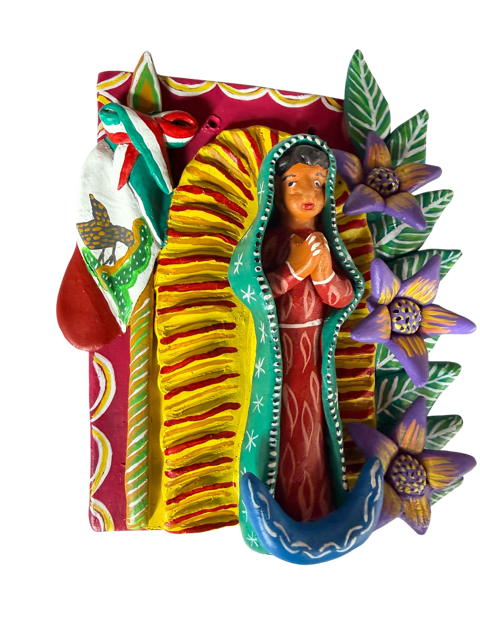 Vista de perfil a tres cuartos de retablo mexicano de barro policromado con base roja y pastillaje floral, disponible en Mansión Iturbe Artisans Collection.