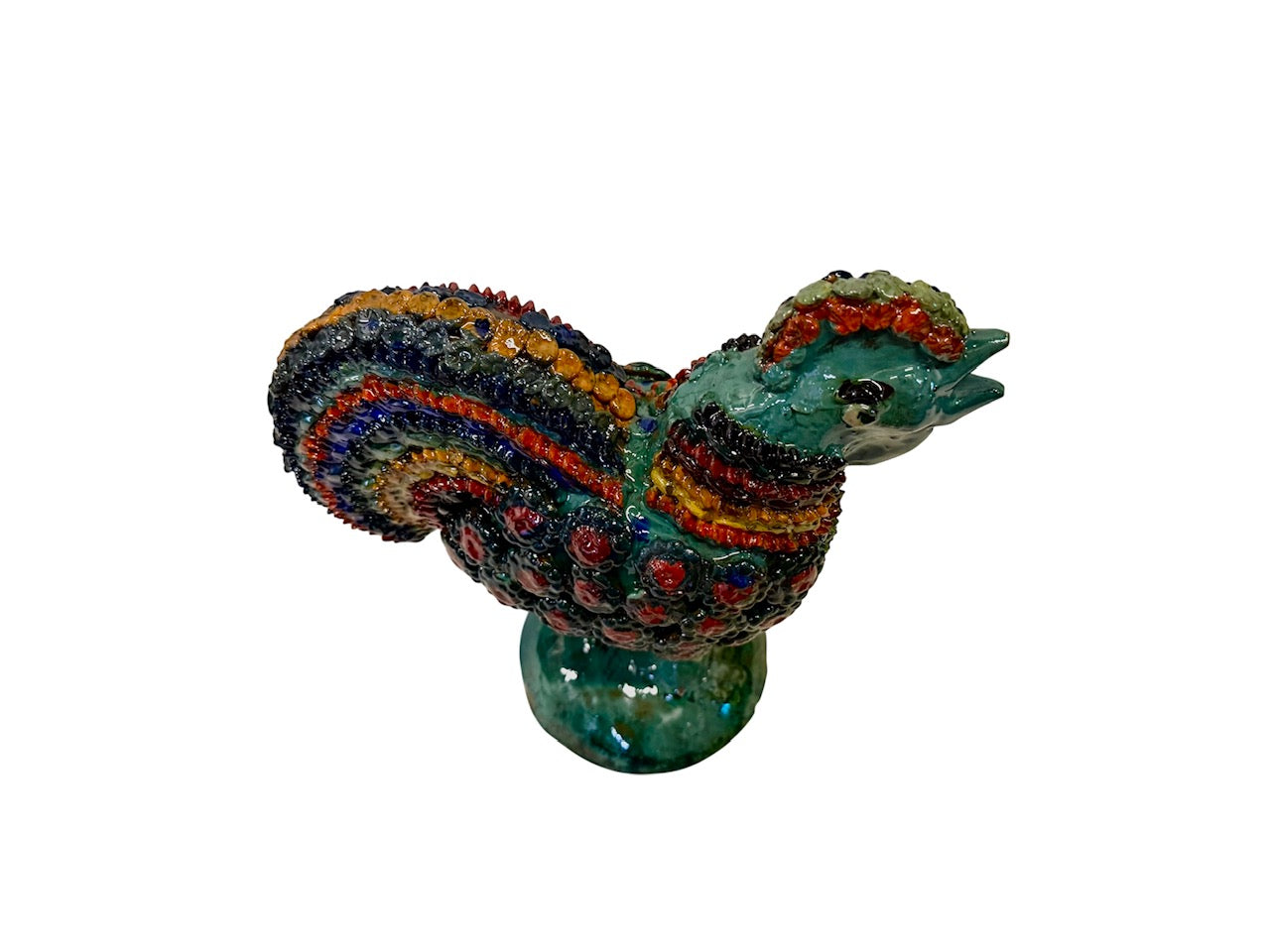 Perspectiva cenital de gallo de barro vidriado resaltando el diseño simétrico del plumaje multicolor y el cuerpo turquesa.