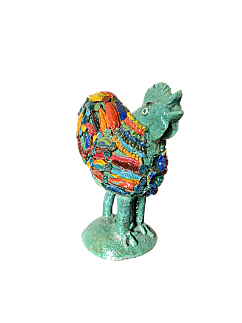 Perspectiva de tres cuartos de gallo de barro turquesa con ranura de alcancía, destacando el relieve tridimensional de flores y pastillaje.